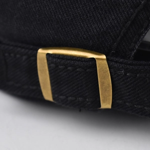 Detailed macro view of the gold metal adjustable buckle and black twill fabric on cap