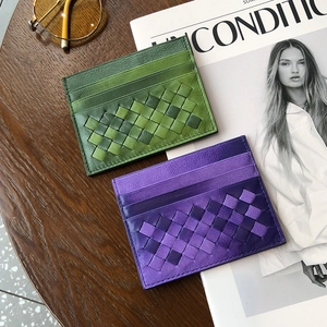 Slim woven sheepskin card holders in green and purple gradient leather on a desk
