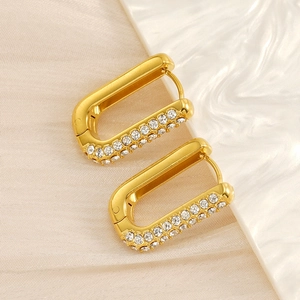 Macro detail of 18K gold plated U-shaped earrings with inlaid crystals on the side