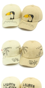 Detail einer gewebten Stroh-Baseballkappe mit besticktem Tukan und tropischen Wellenmotiven