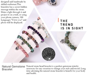 Close-up of gemstone bracelets with heart projection stones and 100 languages text