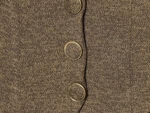 Detail shot of brown knit dress featuring gold-edged buttons and textured knit fabric
