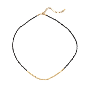 Minimalist black spinel beaded necklace with gold oval metal beads on white background