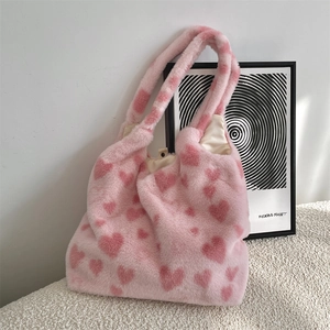 Detail view of pink plush tote bag with red heart patterns and metal snap closure