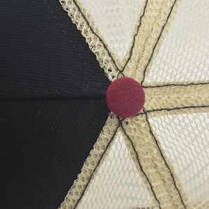 Close-up of baseball cap top with black twill and beige mesh panels with red button