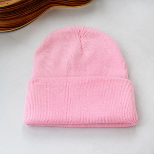 Détail de la texture et du revers d'un bonnet en maille rose sur fond gris clair