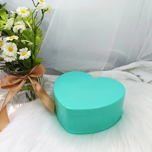 Detalle de joyero en forma de corazón color verde menta sobre superficie de felpa blanca