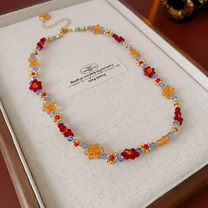 Détail d'un collier à fleurs en perles colorées sur plateau en lin avec fermoir doré