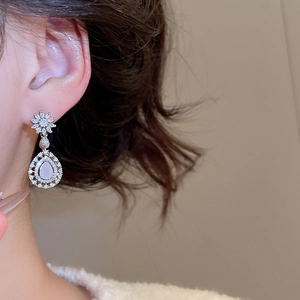 Vue de côté de boucles d'oreilles en argent avec zircons roses et détails de fleurs