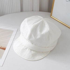 Close-up of white pleated newsboy cap showing delicate vertical textured cotton fabric