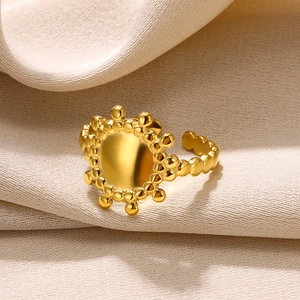 Macro shot of minimalist gold sunburst ring with mirror disc on beige fabric background