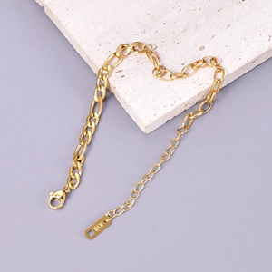 Macro detail of 18k gold plated Figaro chain bracelet with lobster clasp and K18 tag