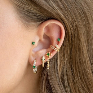 Detailed close-up showing a curated set of gold-plated green and white zirconia earrings.
