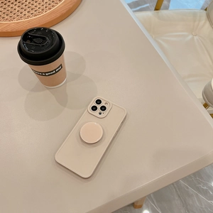 Beige iPhone case with integrated ring stand on a minimalist aesthetic desktop