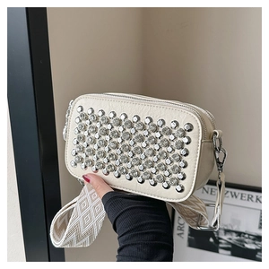 Detail of studded crossbody bag with silver rivets and rhinestone accents on wide strap