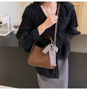 Brown lychee leather bucket bag with checkered scarf shown in a stylish lifestyle scene
