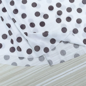 Close-up of white polka dot fabric with brown print on soft breathable chiffon material