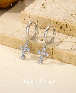 Macro shot of S925 sterling silver cross earrings with opal stones on stone background