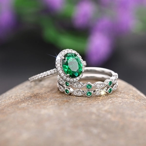 Close-up of emerald green oval ring set with silver-plated bands on a natural stone