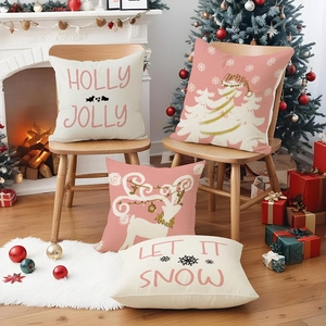 Pink Christmas pillow covers with reindeer and snow motifs in a cozy holiday living room