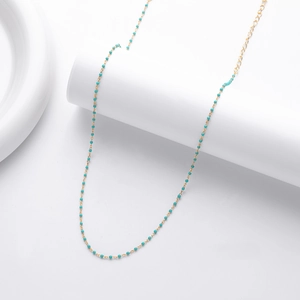 Detail of 925 silver gold plated necklace with turquoise beads on white stand