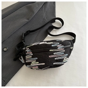 Detail of black crossbody bag featuring colorful wave embroidery and embossed texture