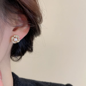 Detailed view of elegant pearl stud earring with pavé rhinestones on model's ear