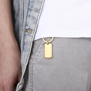 Polished golden square cross pendant hanging from a belt loop as a stylish accessory