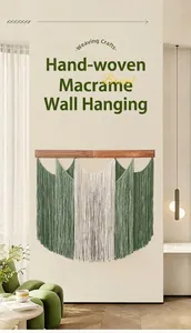 Detail of dark green and beige macrame wall hanging with wooden bar on a cream wall