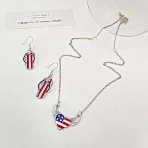 Detail of winged heart necklace and flip-flop earrings with US flag enamel pattern