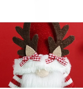 Détail d'un lutin de Noël avec nœud à carreaux rouges et bois en feutre sur fond rouge