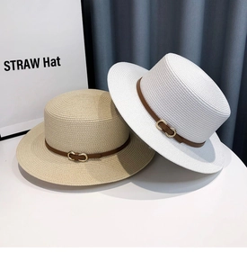 Detail of straw hat texture featuring brown leather strap and golden double-ring buckle