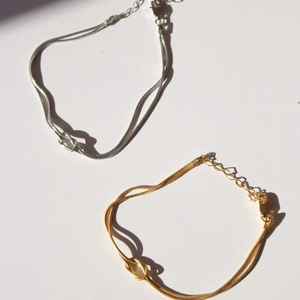 Macro detail of knotted snake chain bracelets in gold and silver with lobster clasp