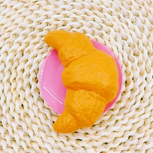 Close-up of golden toy croissant on a pink plate for coffee shop roleplay set