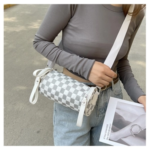 Detailed view of cylindrical crossbody bag with checkered pattern and pleated texture