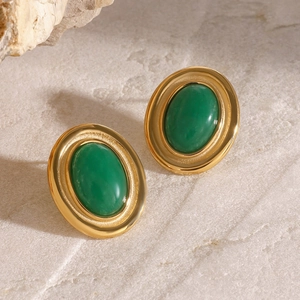 Detailed shot of gold-plated earrings with oval green agate stone on a marble surface