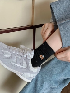 Close-up of black breathable crew sock featuring a detailed brown puppy embroidery accent