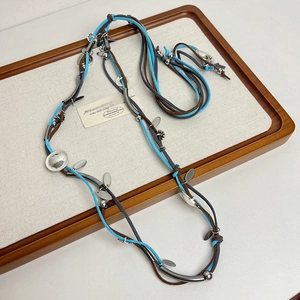 Detail of bohemian handmade braided cord necklace with silver metal charms on linen board