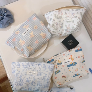Flat lay of four cartoon canvas makeup bags with cute blue patterns and metal zippers