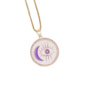 Detail of gold moon and eye enamel pendant with cubic zirconia and a delicate chain