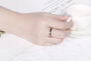 Détail de la bague en acier titane gravée Forever Love portée avec une tasse de café