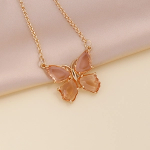 Detailed view of butterfly pendant necklace with translucent orange crystals on silk