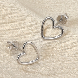 Elegant S925 sterling silver hollow heart stud earrings on luxury silk fabric background