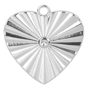 Macro shot of silver heart pendant with sunburst texture and polished steel finish