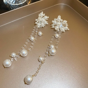 Detail of floral pearl and crystal fringe earrings on champagne metal tray