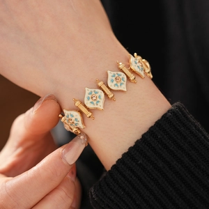 Detail of vintage gold bracelet with white enamel, blue floral patterns and small diamonds