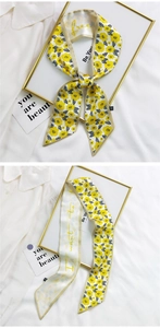 Close-up of a long yellow floral silk scarf with 'free' lettering and gold edges