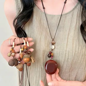 Ethnic style long sweater necklace with handmade wooden acorns and feather pendant