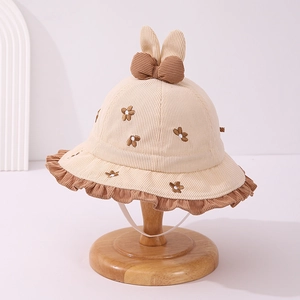 Dettaglio cappello in velluto beige per bambini con orecchie di coniglio e ricami floreali