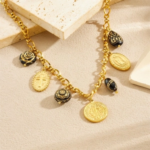 Vintage gold chain necklace with black relief charms on a textured stone background